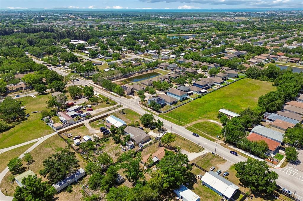 An aerial view shows a suburban neighborhood with houses, a pond, and green spaces — 1611 E SHELL POINT ROAD, RUSKIN, FL