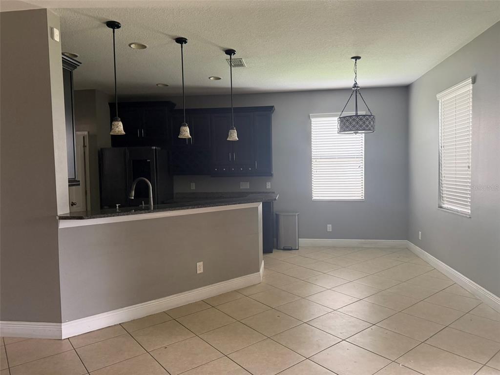 A kitchen with dark cabinets, a breakfast bar, and a dining area with tile flooring — 1863 ALTAVISTA CIRCLE, LAKELAND, FL