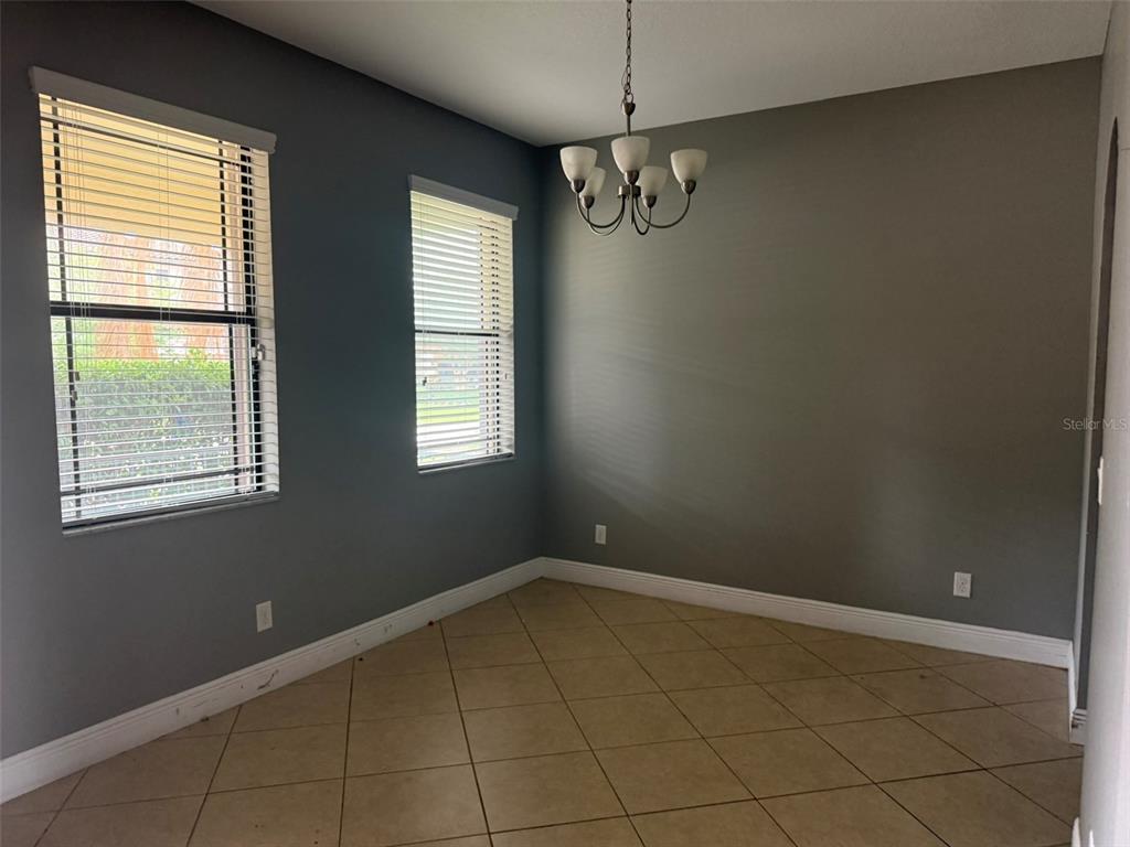 A dining room with gray walls, tile flooring, two windows with blinds, and a chandelier — 1863 ALTAVISTA CIRCLE, LAKELAND, FL