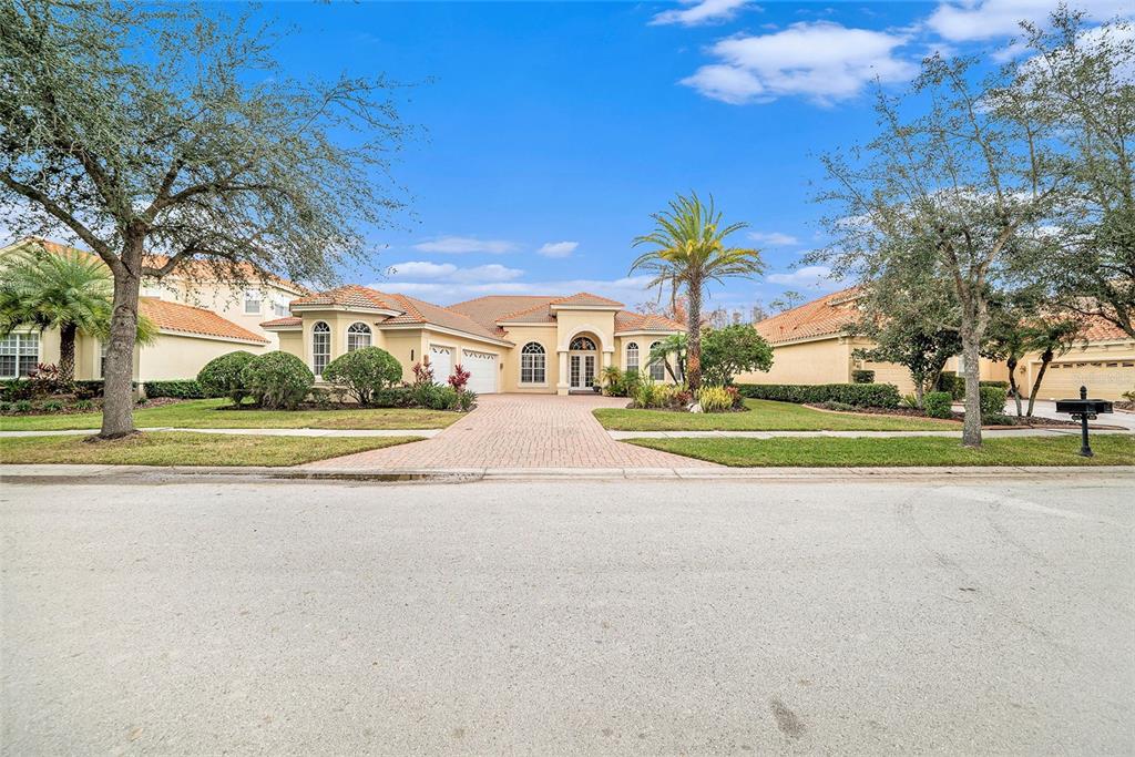 A single-story house with a tan stucco exterior, a tile roof, and a brick driveway — 8478 DUNHAM STATION DRIVE, TAMPA, FL