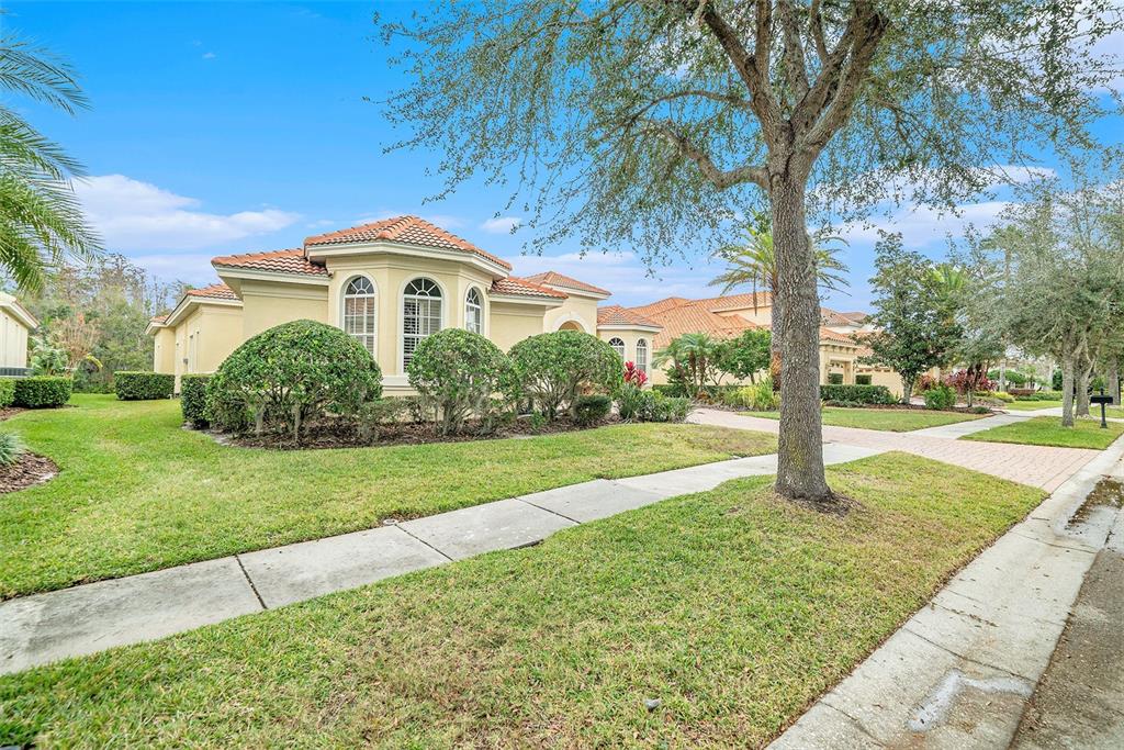 A single-story house with a tile roof and arched windows sits behind a manicured lawn — 8478 DUNHAM STATION DRIVE, TAMPA, FL