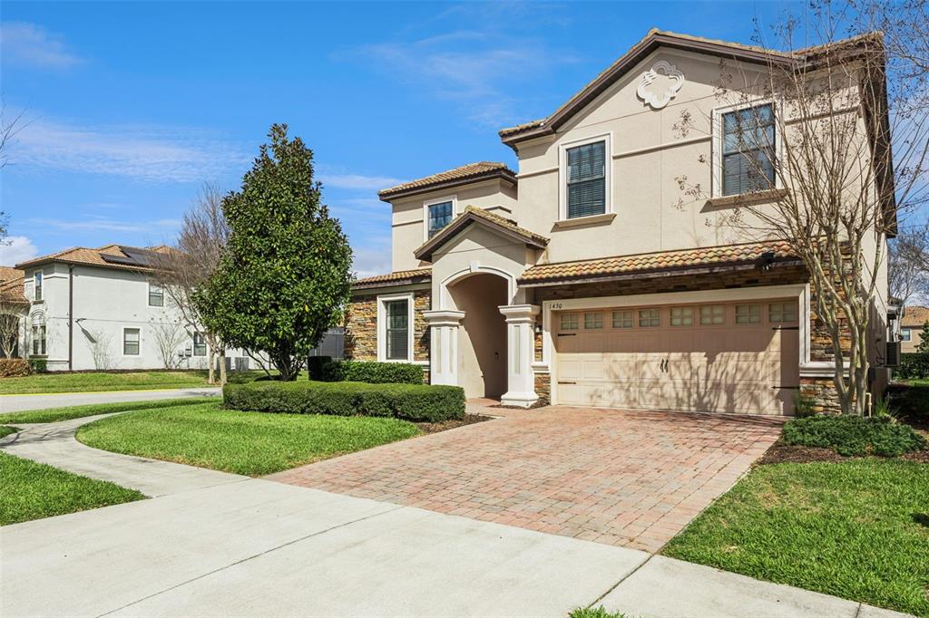 A two-story stucco house with a stone facade, tile roof, and a brick paver driveway — 1430 MOON VALLEY DRIVE, DAVENPORT, FL