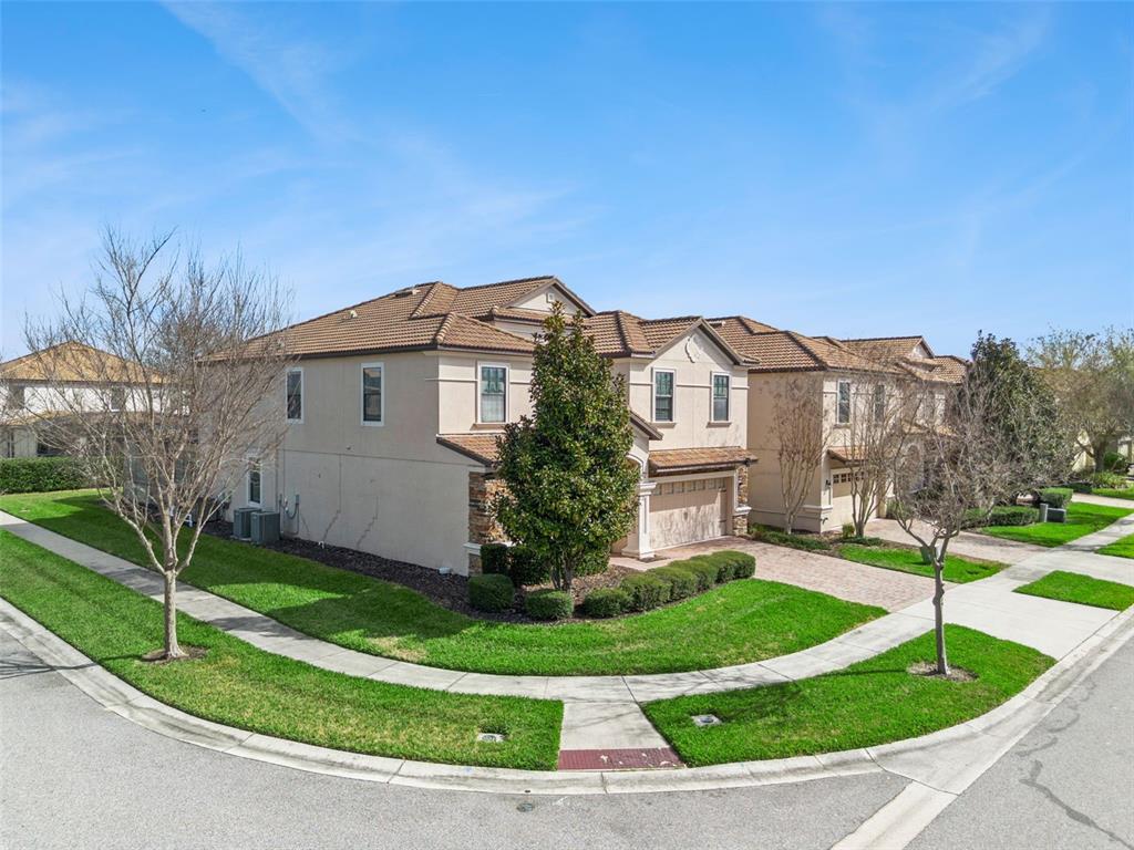 A two-story stucco townhouse with a tile roof sits on a corner lot — 1430 MOON VALLEY DRIVE, DAVENPORT, FL