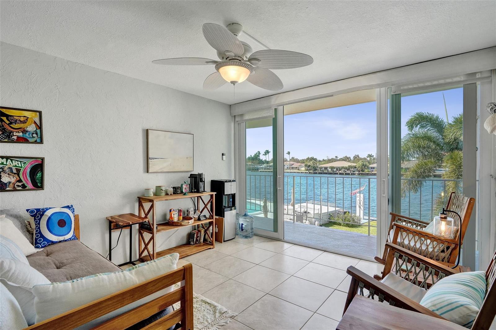A living room with tile floors, a ceiling fan, and sliding doors overlooking a canal — 801 N Riverside Drive # 4b, Pompano Beach FL 33062, POMPANO BEACH, FL