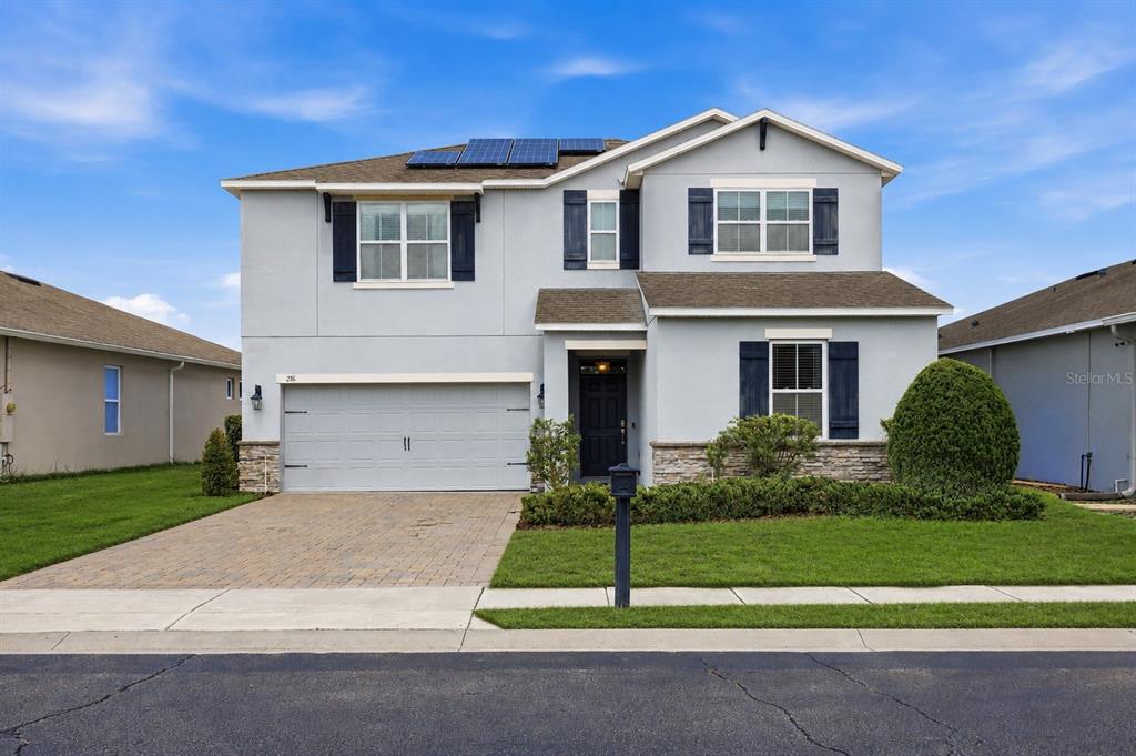 A two-story suburban house with a gray stucco exterior, a two-car garage, and solar panels — 276 DRAYTON AVENUE, DAVENPORT, FL