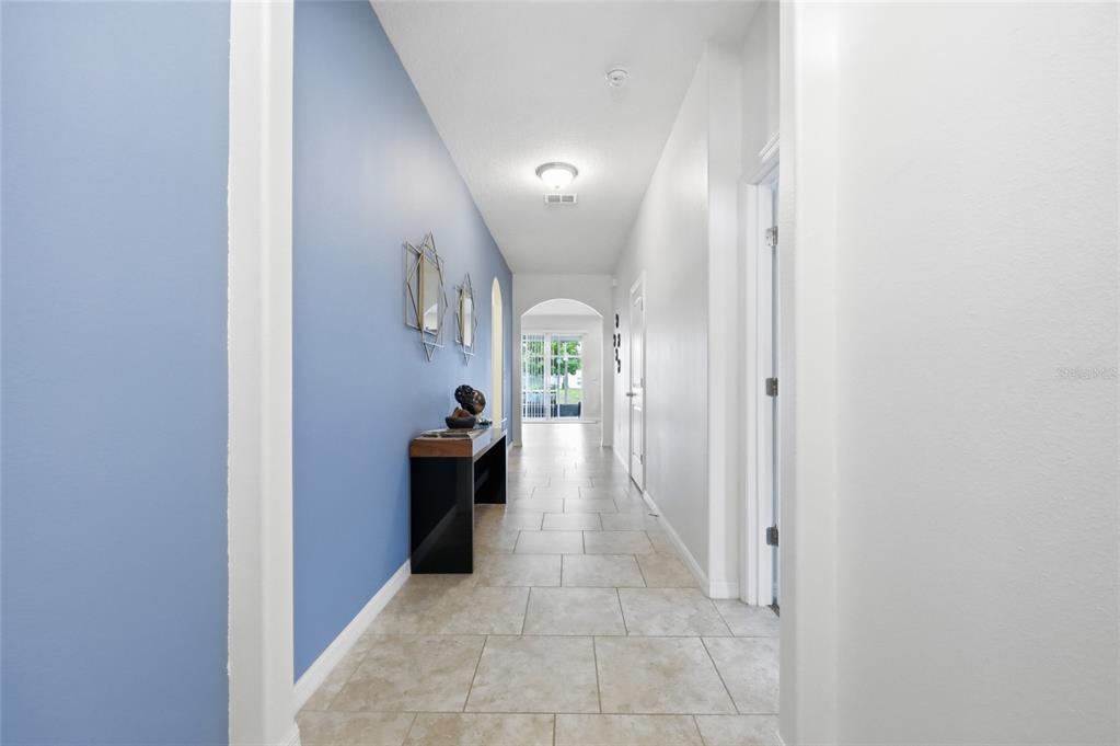 A hallway with light tile flooring, a blue accent wall, and a console table — 276 DRAYTON AVENUE, DAVENPORT, FL