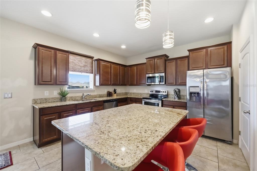 A kitchen features dark wood cabinets, granite countertops, stainless steel appliances, and a central island — 276 DRAYTON AVENUE, DAVENPORT, FL