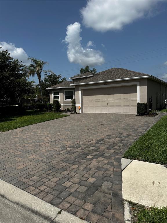 A single-story house with a beige exterior, a two-car garage, and a paved driveway — 262 LAKE MARIANA PLACE, AUBURNDALE, FL