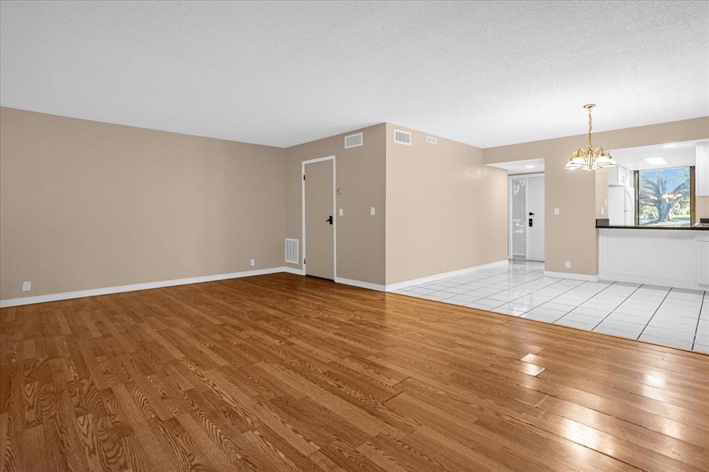 An open-concept living room features hardwood flooring, beige walls, and a tiled dining area — 411 SHEOAH BOULEVARD UNIT 43, WINTER SPRINGS, FL