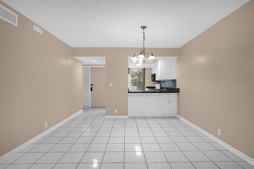 A dining area with white tile floors, beige walls, and a kitchen pass-through window — 411 SHEOAH BOULEVARD UNIT 43, WINTER SPRINGS, FL