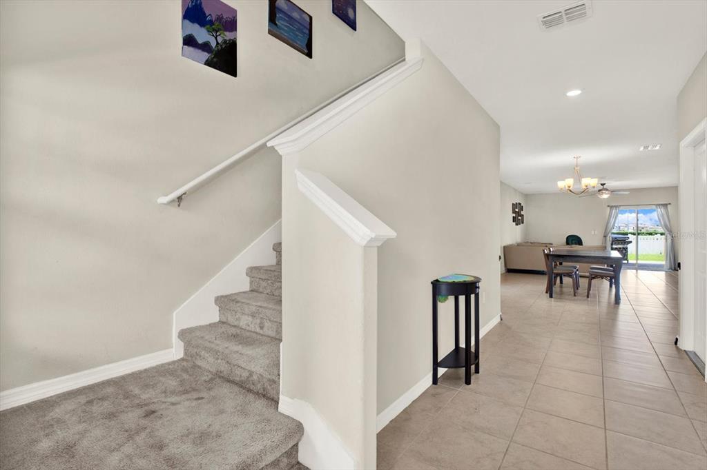 A carpeted staircase leads upward next to a tiled hallway opening into a dining area — 7505 SAMUEL IVY DRIVE, TAMPA, FL