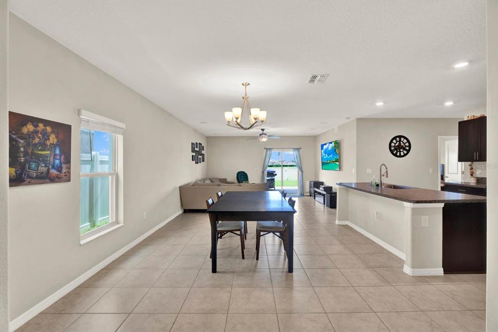 An open-concept dining and living area features tile flooring, a kitchen island, and sliding doors — 7505 SAMUEL IVY DRIVE, TAMPA, FL