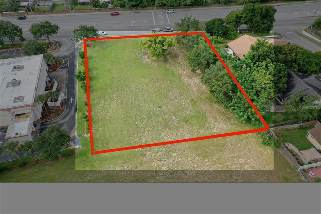 An aerial view shows a rectangular, undeveloped grassy lot outlined in red — OLD WINTER GARDEN ROAD, ORLANDO, FL