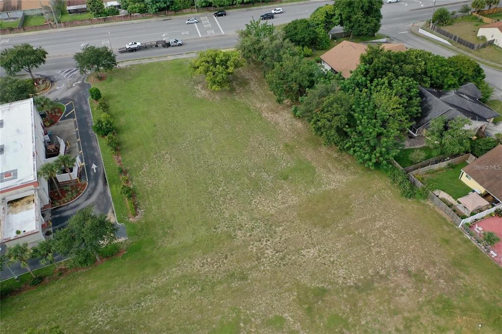 An aerial view shows a vacant, grassy lot situated next to a commercial building and houses — OLD WINTER GARDEN ROAD, ORLANDO, FL