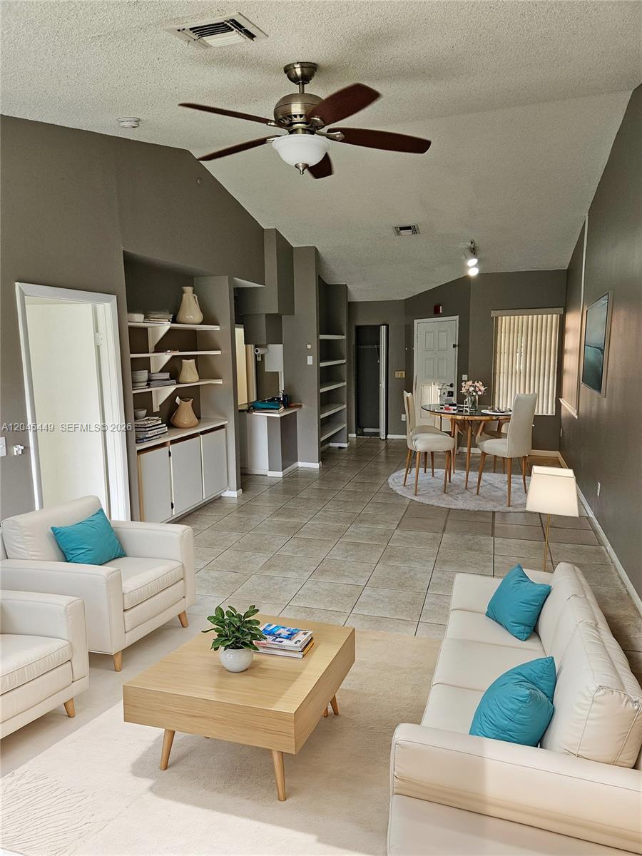 A living and dining area features tile floors, white furniture, and built-in shelving — 18306 NW 68th Ave # H, Hialeah FL 33015, HIALEAH, FL