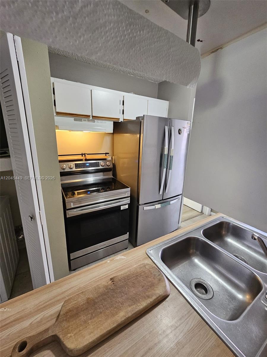 A kitchen features stainless steel appliances, white cabinets, and a double-basin sink — 18306 NW 68th Ave # H, Hialeah FL 33015, HIALEAH, FL