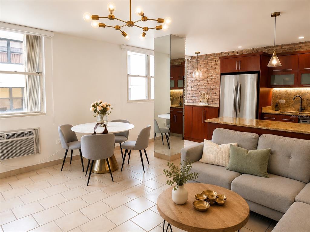 An open-concept living and dining area features a brick accent wall, tile flooring, and kitchen — 1305 MAGDALENA AVENUE UNIT 10B, SAN JUAN, PR