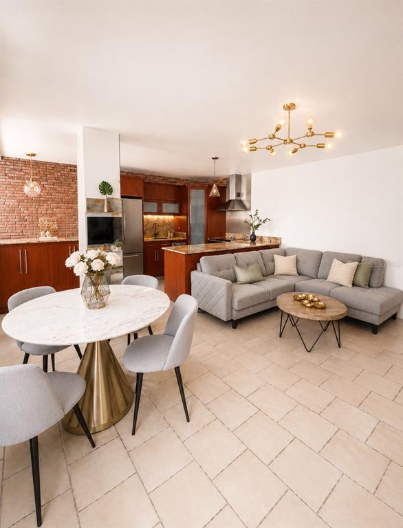 An open-concept living and dining area features a marble table, gray sectional, and brick wall — 1305 MAGDALENA AVENUE UNIT 10B, SAN JUAN, PR