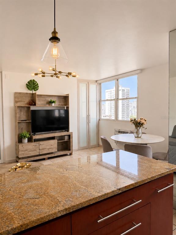 A kitchen island with granite countertops overlooks a living area with a television console — 1305 MAGDALENA AVENUE UNIT 10B, SAN JUAN, PR