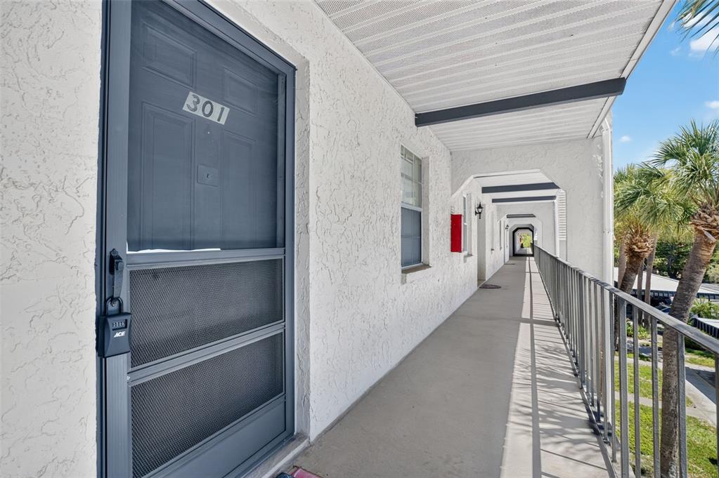 An exterior walkway leads past a door numbered 301 with a gray screen door — 8693 BARDMOOR BOULEVARD UNIT 301B, LARGO, FL
