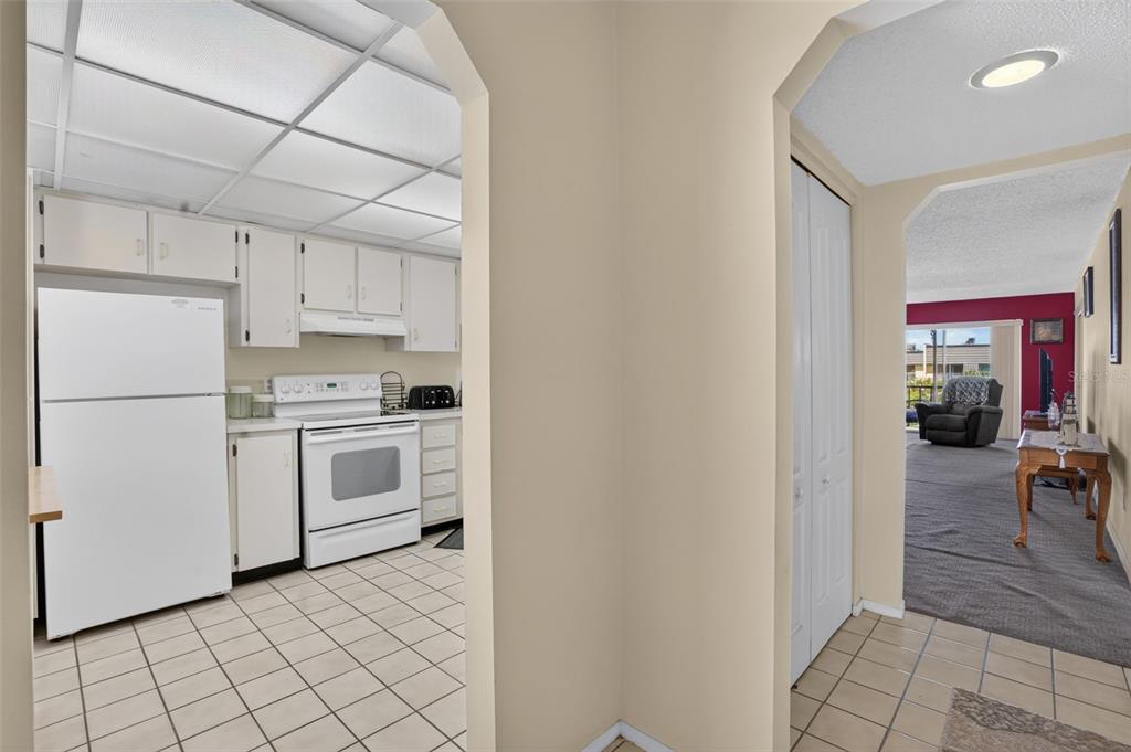 A view through an arched doorway into a kitchen with white appliances and tiled floors — 8693 BARDMOOR BOULEVARD UNIT 301B, LARGO, FL