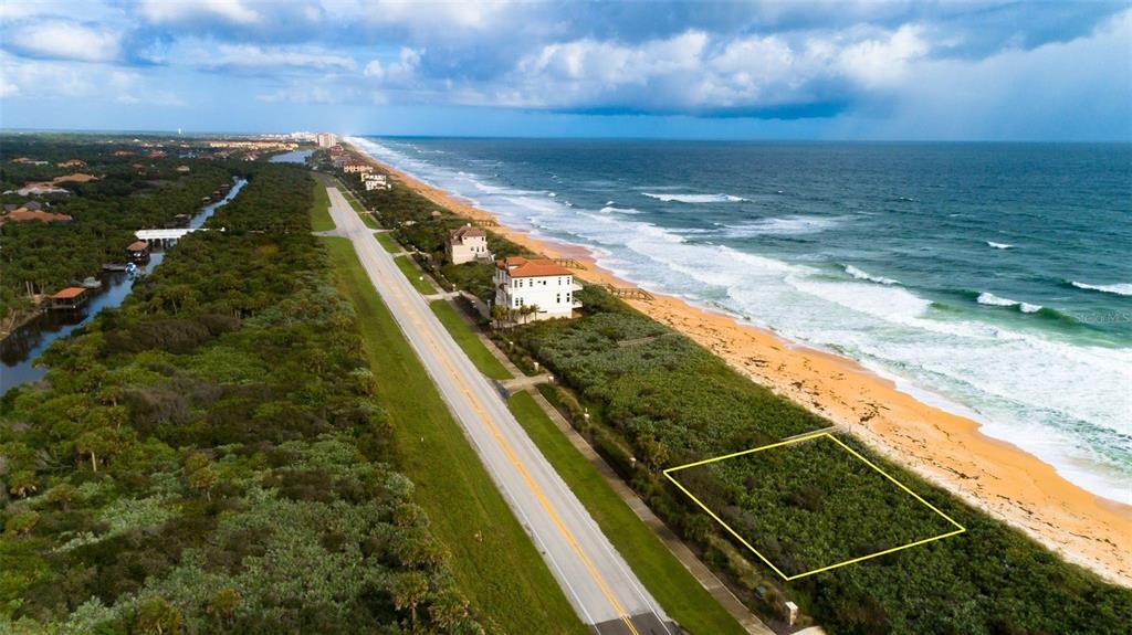 An aerial view shows a vacant oceanfront lot outlined in yellow next to a coastal road — 3721 N OCEAN SHORE BOULEVARD, PALM COAST, FL