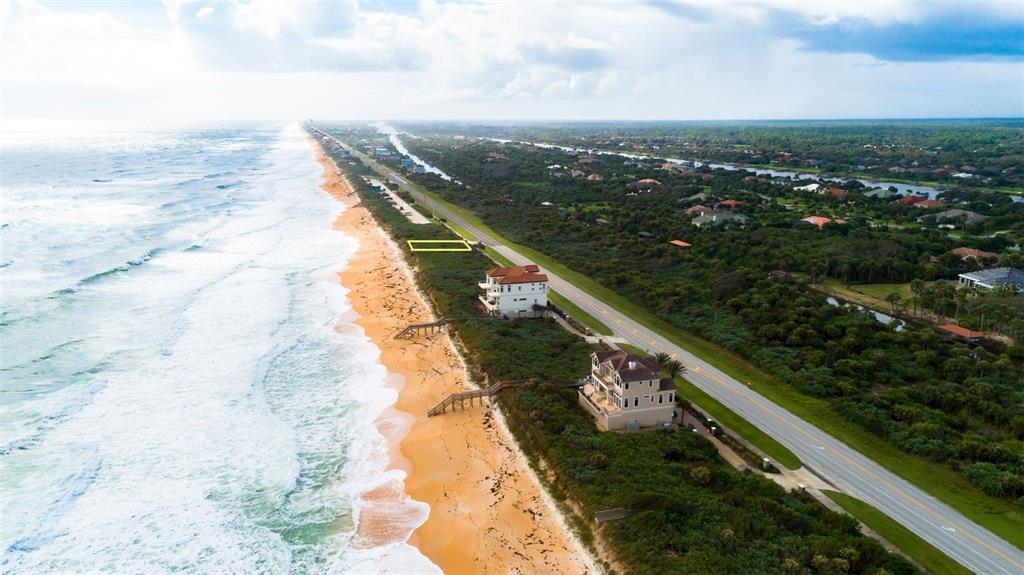 An aerial view shows a vacant coastal lot outlined in yellow between a road and beach — 3721 N OCEAN SHORE BOULEVARD, PALM COAST, FL