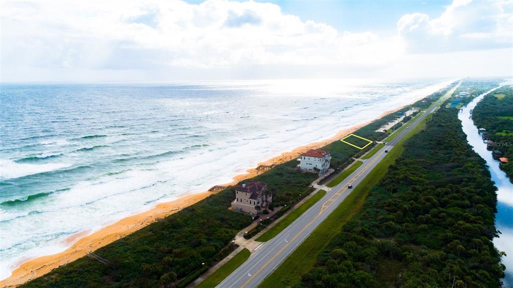 An aerial view shows a vacant beachfront lot highlighted by a yellow rectangle near houses — 3721 N OCEAN SHORE BOULEVARD, PALM COAST, FL