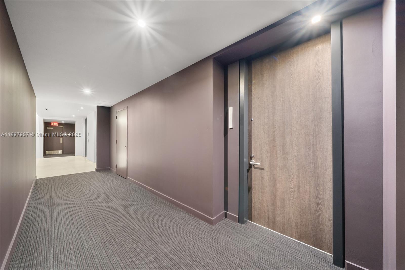 A hallway features dark walls, gray carpet, and a wood-toned door with metal trim — 88 SW 7th St # 3910, Miami FL 33130, MIAMI, FL