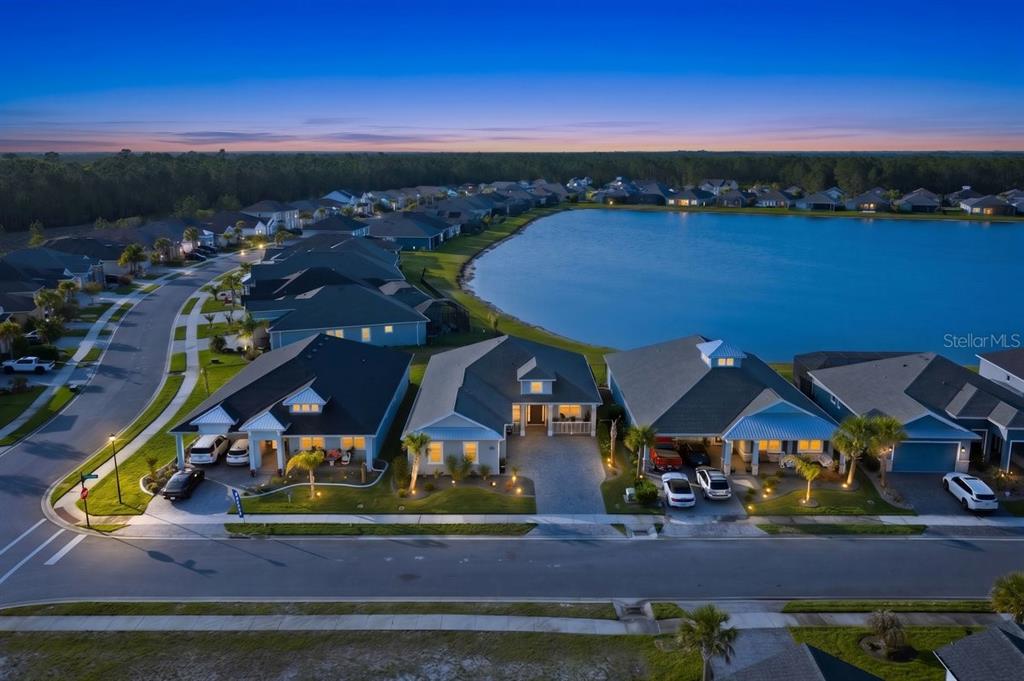 An aerial view of a suburban neighborhood with houses bordering a large lake at dusk — 260 FUCHSIA STREET, DAYTONA BEACH, FL