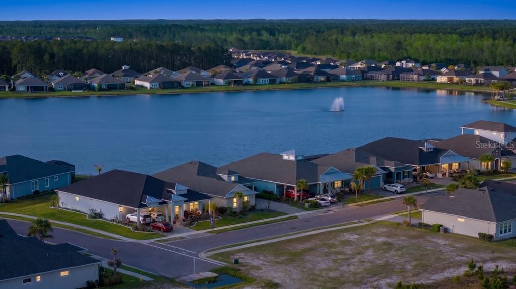 An aerial view of a suburban neighborhood featuring houses surrounding a large lake with a fountain — 260 FUCHSIA STREET, DAYTONA BEACH, FL