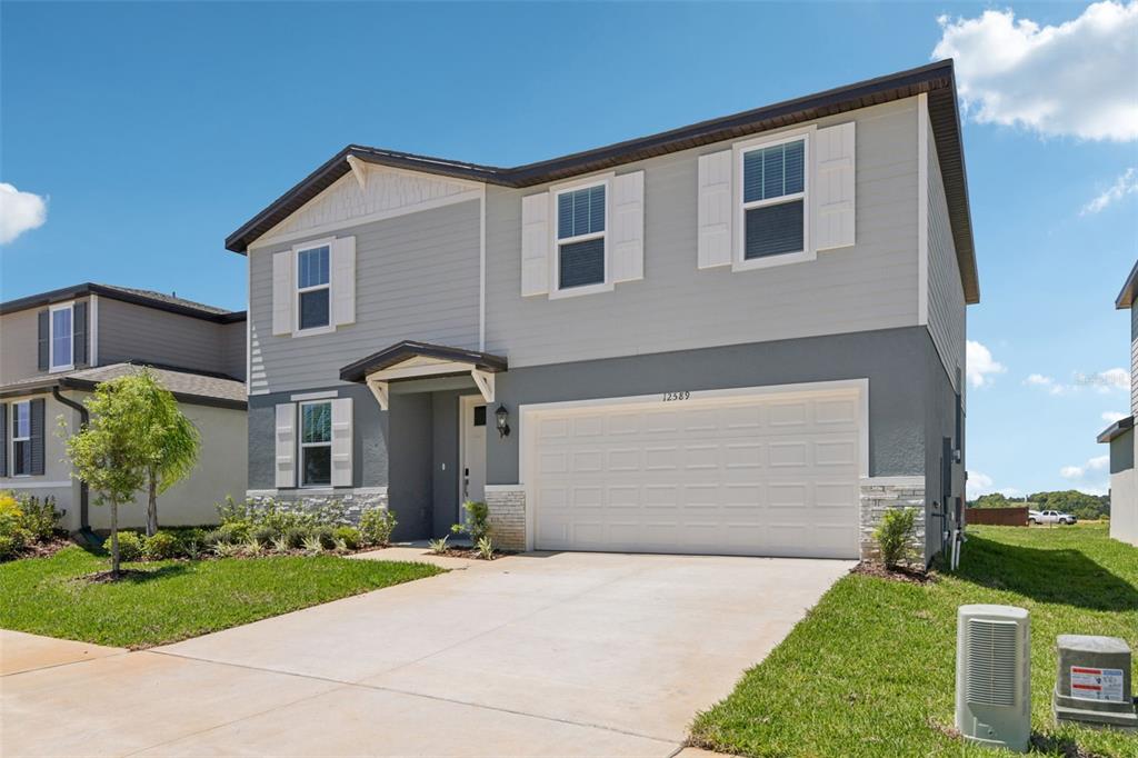 A two-story house with a gray exterior, white shutters, and a two-car garage — 12589 HOMELAND DRIVE, DADE CITY, FL