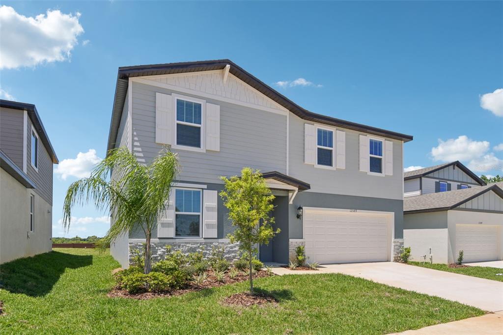 A two-story suburban house with gray siding, white shutters, and a two-car garage — 12589 HOMELAND DRIVE, DADE CITY, FL