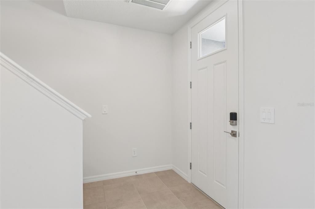 An entryway with white walls, tile flooring, and a white door with a smart lock — 12589 HOMELAND DRIVE, DADE CITY, FL