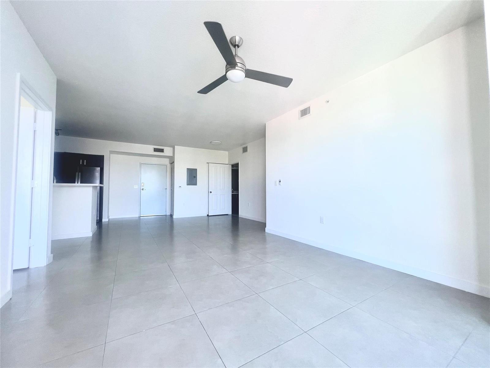 An open-concept living area features light-colored tile flooring, white walls, and a ceiling fan — 729 NW 2 Street # 501, Miami FL 33128, MIAMI, FL