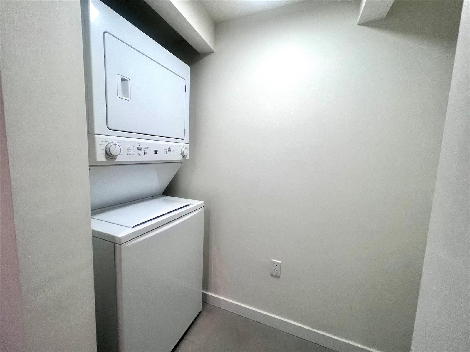 A white stacked washer and dryer unit sits in a small laundry closet — 729 NW 2 Street # 501, Miami FL 33128, MIAMI, FL