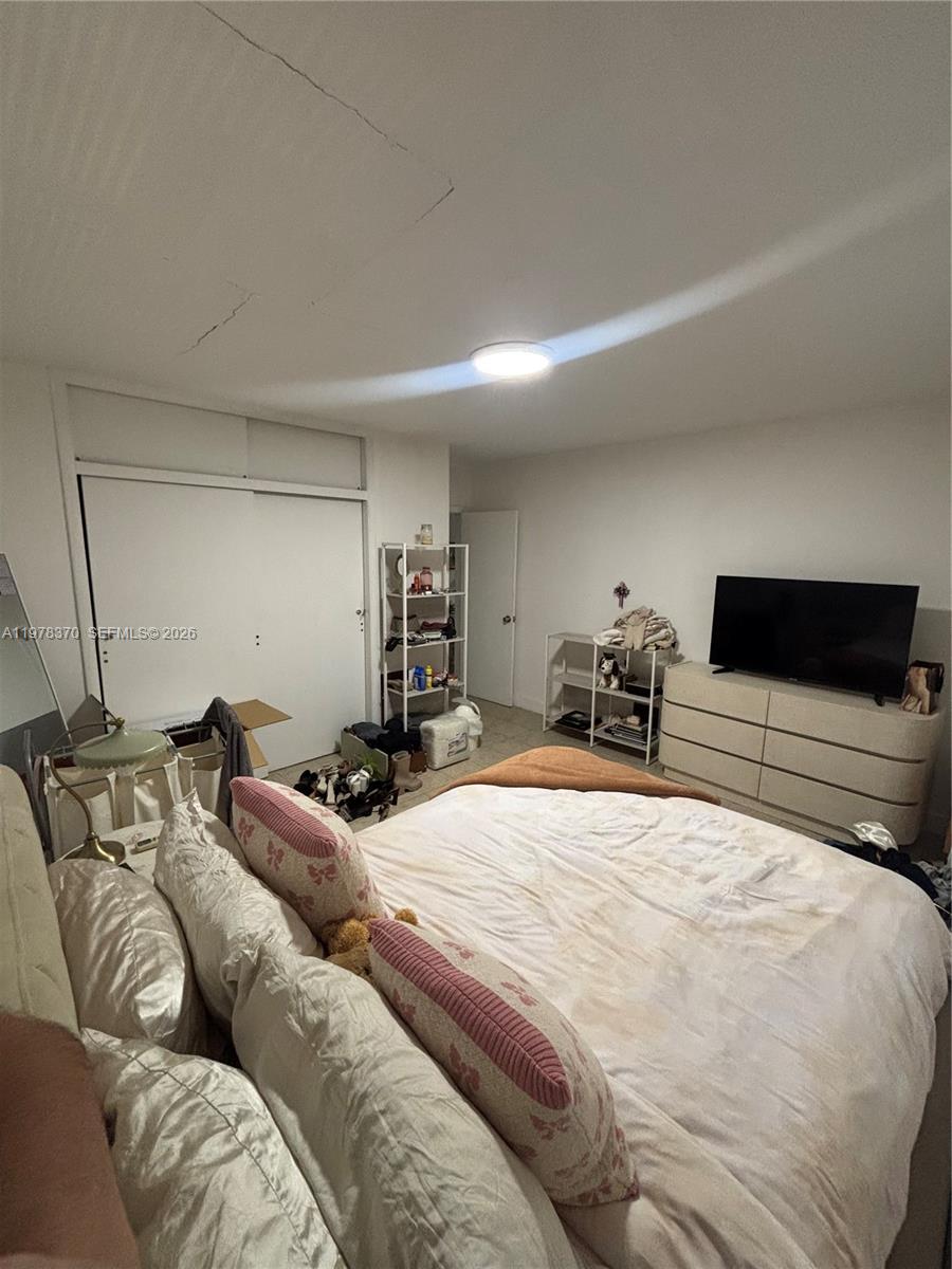 A bedroom features a bed with white bedding, a dresser with a television, and shelving — 75 Washington Ave # 12A, Miami Beach FL 33139, MIAMI BEACH, FL
