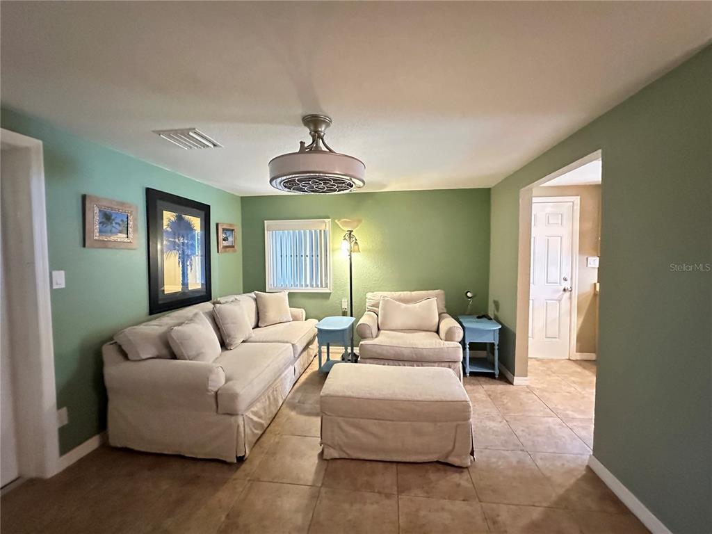 A living room features light-colored furniture, green walls, tile flooring, and a ceiling fan — 1230 WOODLAWN AVENUE, PUNTA GORDA, FL