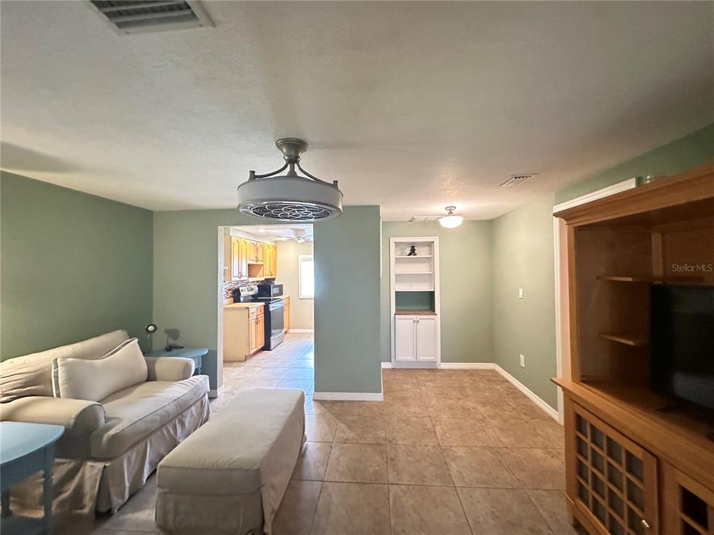 A living room with light green walls, tile flooring, a sofa, and an adjacent kitchen — 1230 WOODLAWN AVENUE, PUNTA GORDA, FL