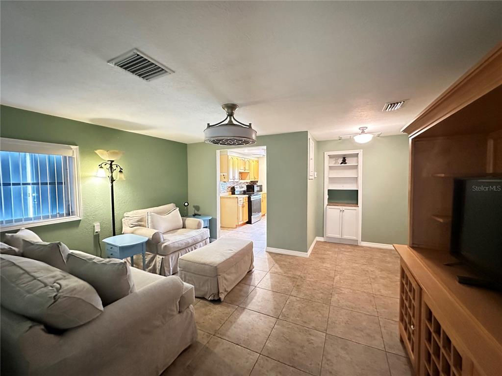 A living room with tile floors, sage green walls, and an opening to the kitchen — 1230 WOODLAWN AVENUE, PUNTA GORDA, FL