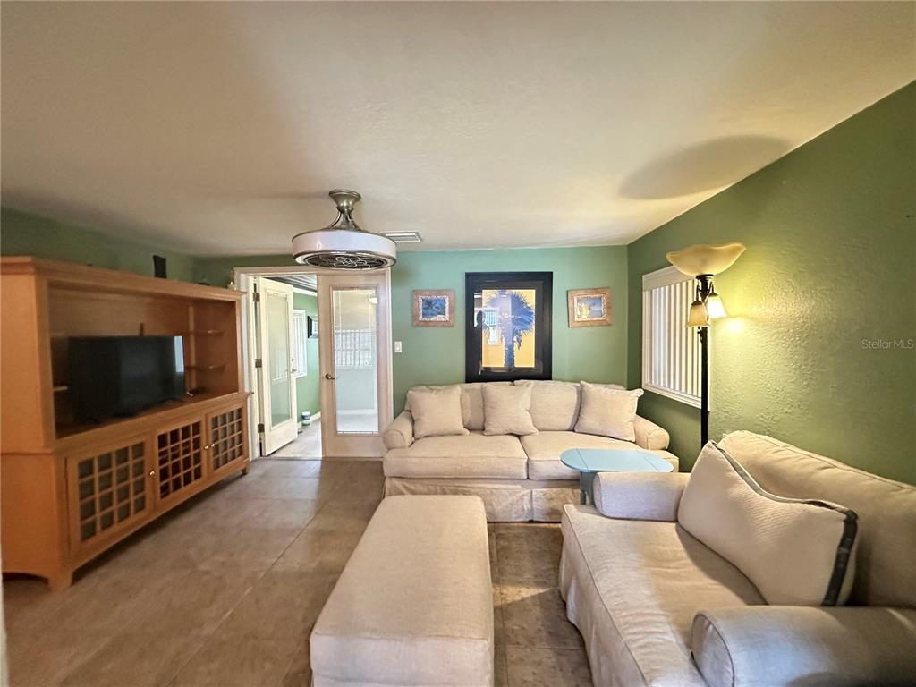 A living room features light green walls, two sofas, a large wooden entertainment center, and tile flooring — 1230 WOODLAWN AVENUE, PUNTA GORDA, FL
