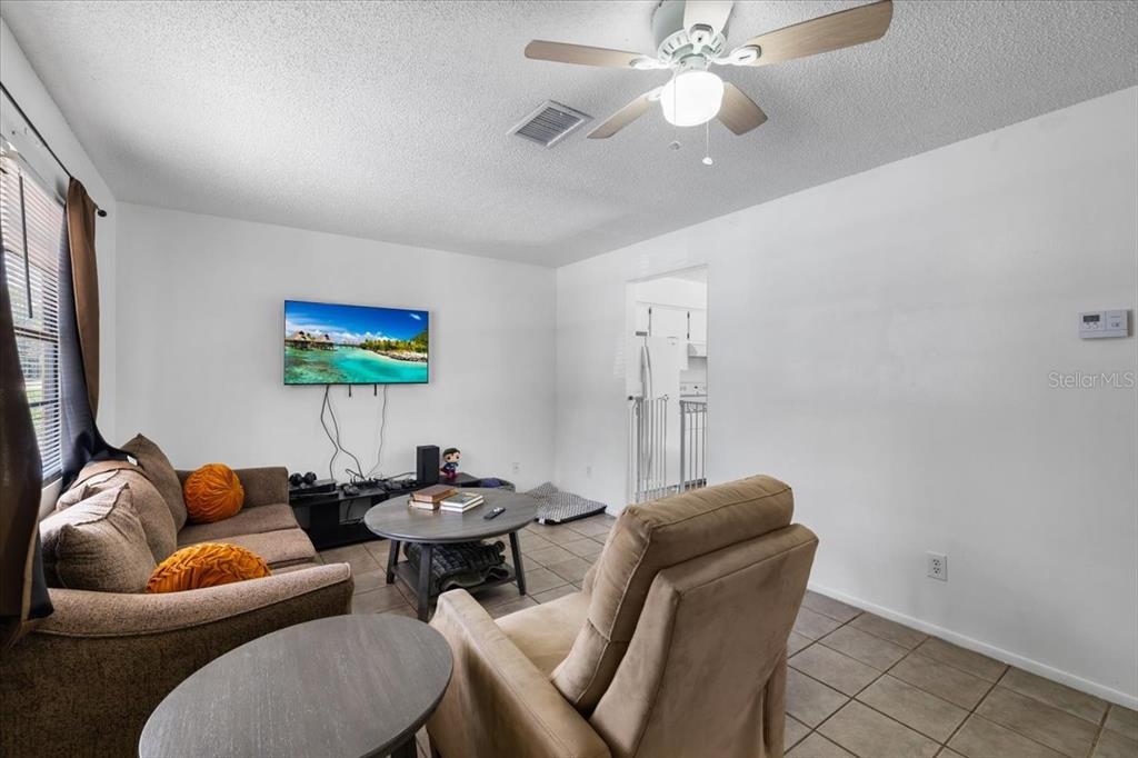 A living room with tile floors, a ceiling fan, a sofa, and a wall-mounted television — 3135 S LANTANA WAY, HOMOSASSA, FL