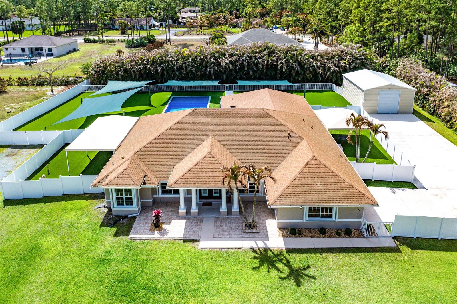 A backyard features a rectangular swimming pool, a patio, and a detached outdoor kitchen area — 15436 66th Court N, Loxahatchee FL 33470, LOXAHATCHEE, FL