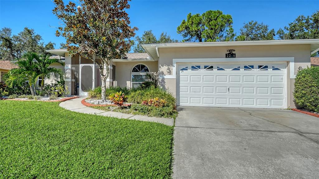 A single-story house with a white garage door, a front walkway, and a landscaped yard — 2246 CORK OAK STREET W, SARASOTA, FL