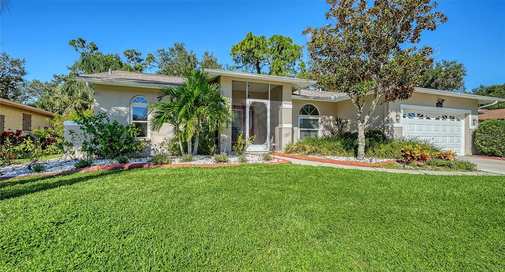 A single-story house with a white garage door, a screened entryway, and a green lawn — 2246 CORK OAK STREET W, SARASOTA, FL
