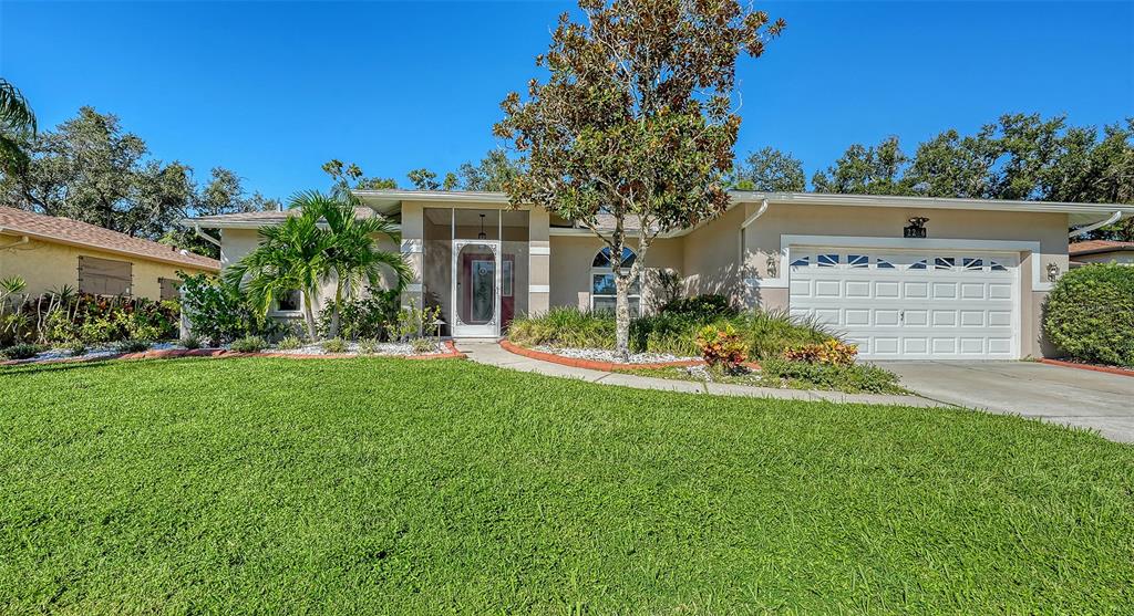 A single-story house with a white garage, a front lawn, and a large central tree — 2246 CORK OAK STREET W, SARASOTA, FL