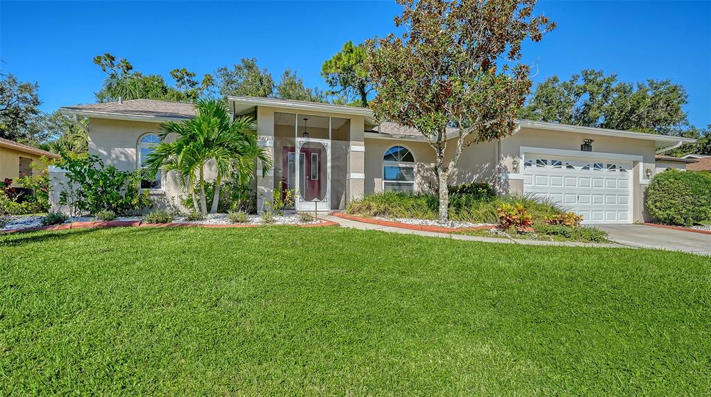 A single-story house with a white garage, a screened entryway, and a green lawn — 2246 CORK OAK STREET W, SARASOTA, FL
