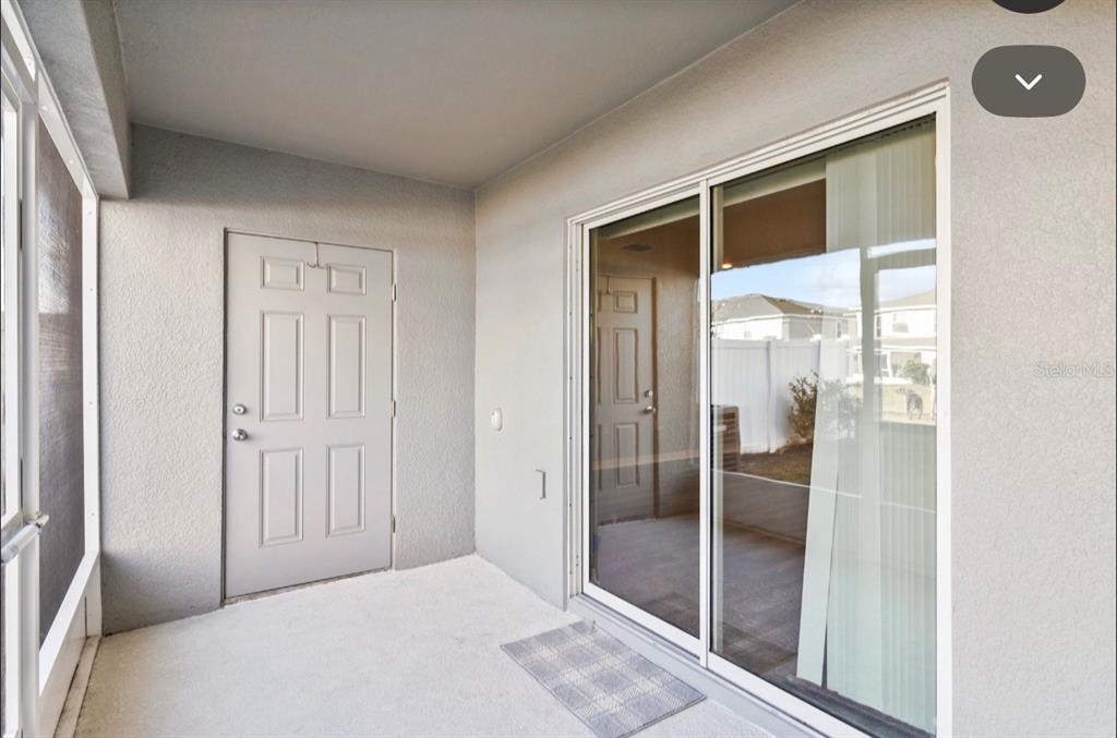 A covered patio with a gray door, sliding glass doors, and a concrete floor — 2917 FIELDWOOD CIRCLE, ST CLOUD, FL