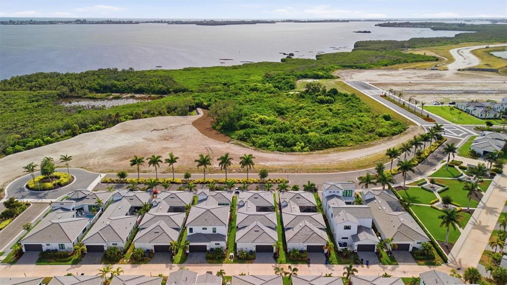 An aerial view shows a row of modern houses near a coastal mangrove area — 6027 SALT GRASS STREET, BRADENTON, FL
