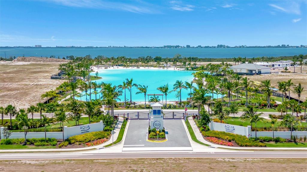 An aerial view shows a gated entrance leading to a large turquoise lagoon — 6027 SALT GRASS STREET, BRADENTON, FL
